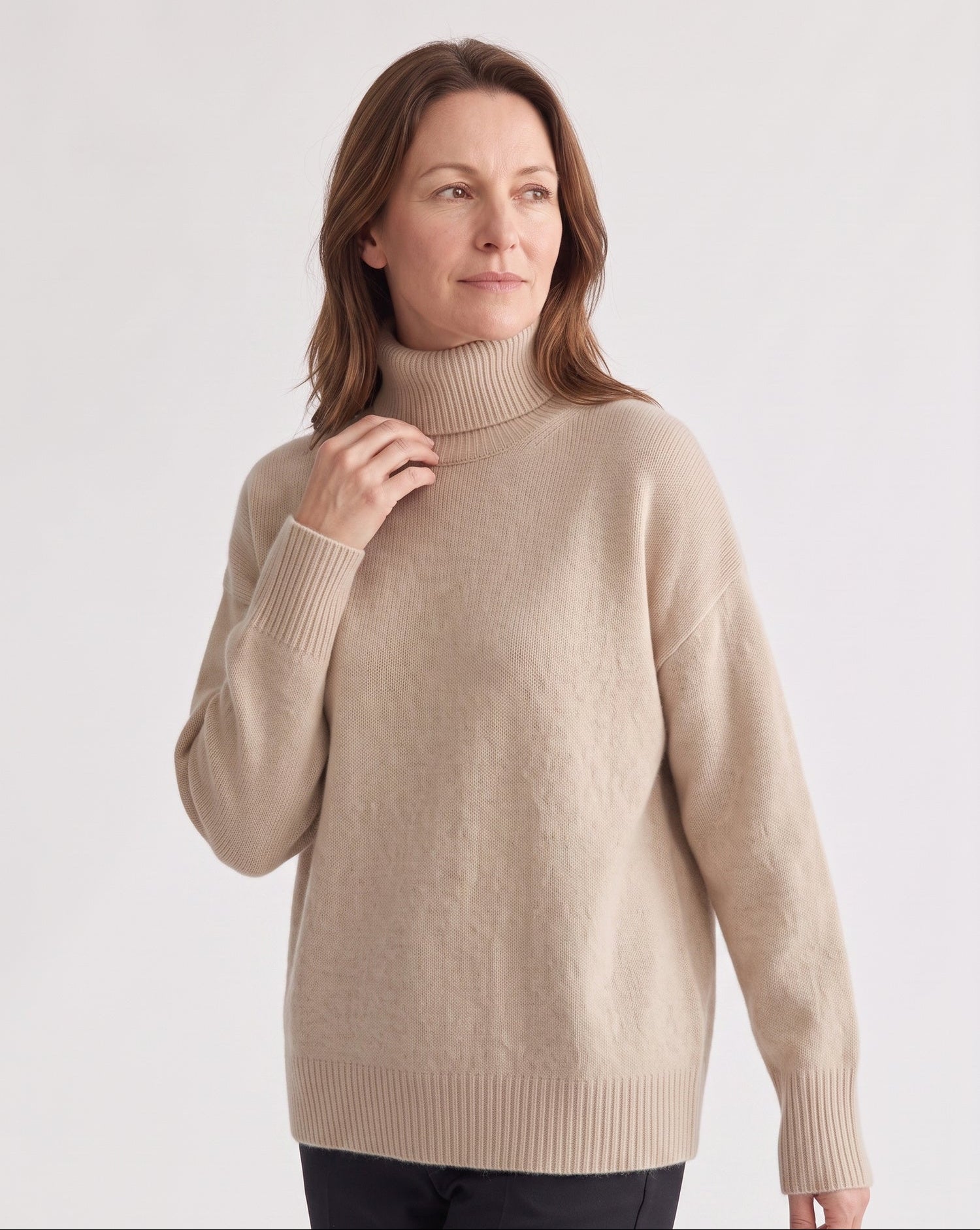 Femme en pull oversize col roulé camel, studio gris clair